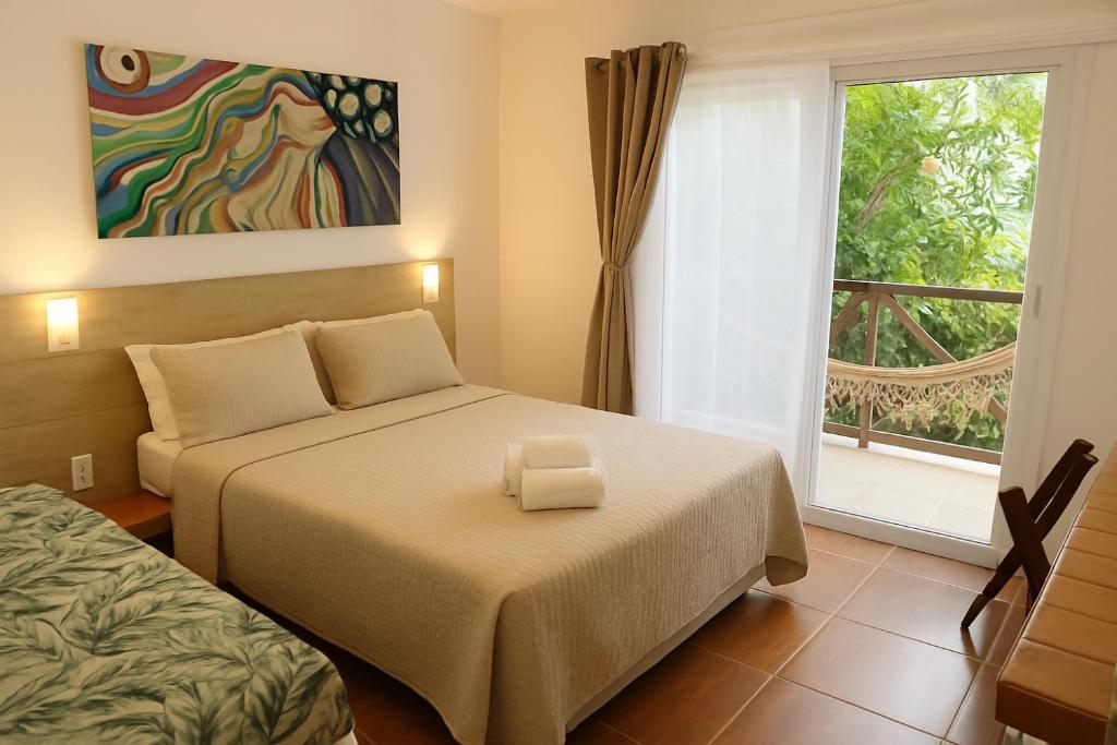 a hotel room with two beds and a window at Pousada Borboleta in Morro de São Paulo