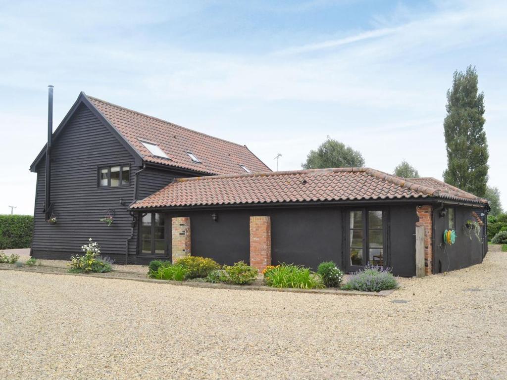 a black house with a red roof at Burfields Barn in Rickinghall