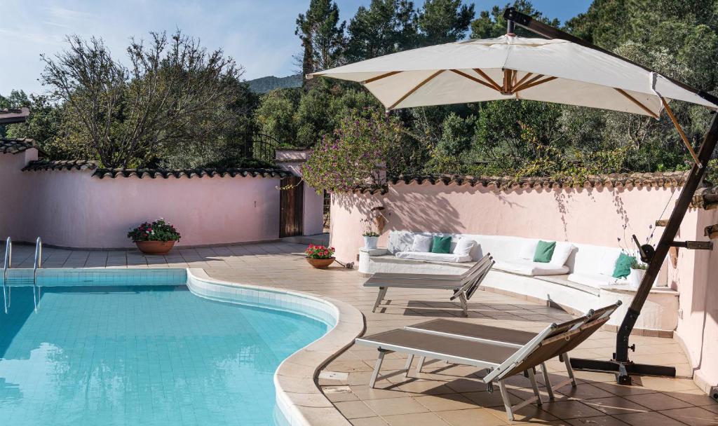 a pool with two chairs and an umbrella at Villa Fiori 4 in Is Molas 