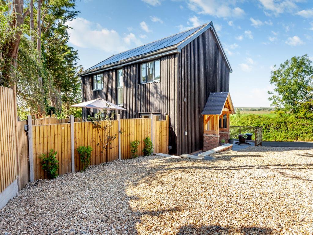 een houten huis met een hek en een grindpad bij Willow House in Worle