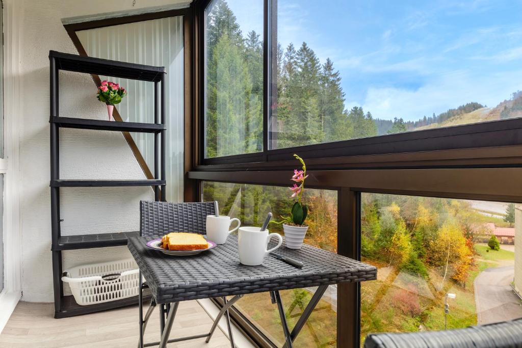 einen Tisch und Stühle auf einem Balkon mit einem großen Fenster in der Unterkunft Kamélia - 10min des pistes in Xonrupt-Longemer