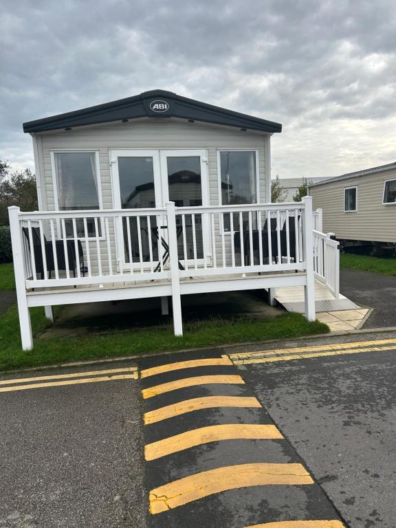 une maison blanche avec un porche en bord de route dans l'établissement Haven Blackpool Fleetwood holiday park, à Fleetwood