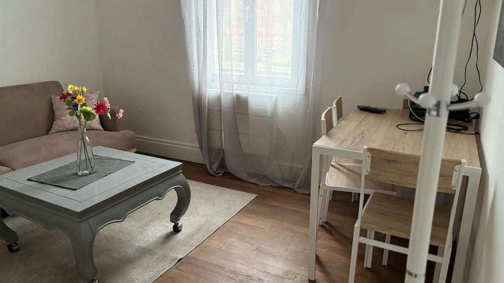 a living room with a table with a vase of flowers on it at T2 proche du CH d'Arras in Sainte-Catherine