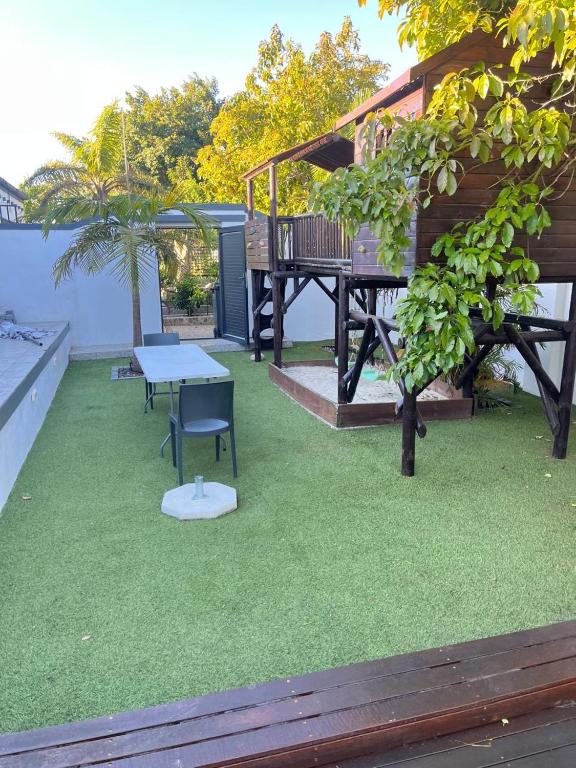 a patio with a table and a bench on the grass at Black chilli accommodation in Brackenfell
