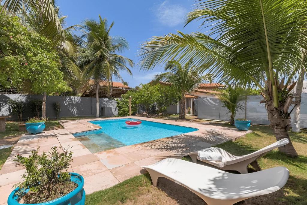 a backyard with a swimming pool and palm trees at Casa Dunas - Espaço e Conforto em PDD by Carpediem in Aquiraz