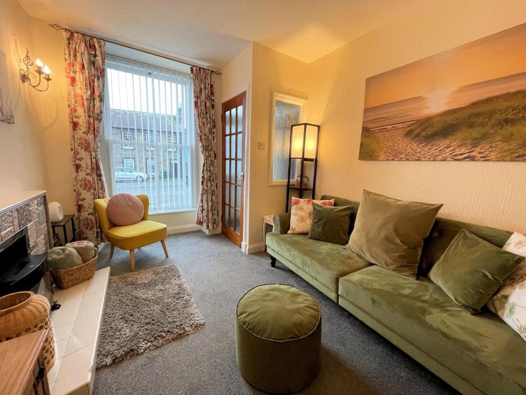 a living room with a green couch and a window at Pass the Keys Cosy Romantic Getaway with Hot Tub in Whithorn