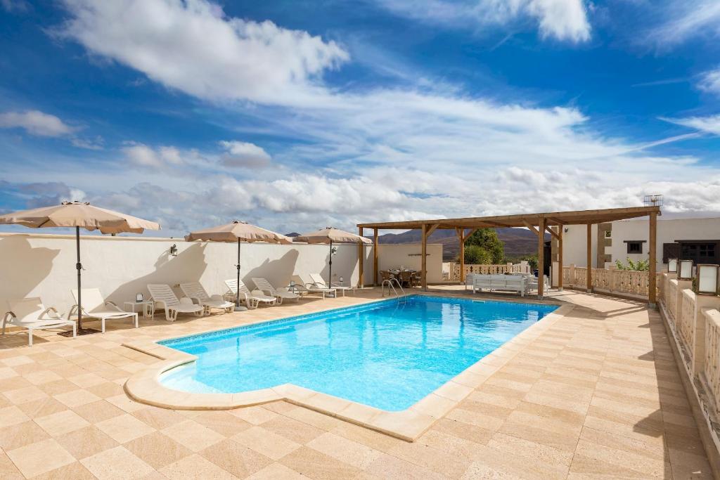 a swimming pool with chairs and umbrellas on a patio at Home2Book Serenity Villa with Private Pool in Casillas del Ángel