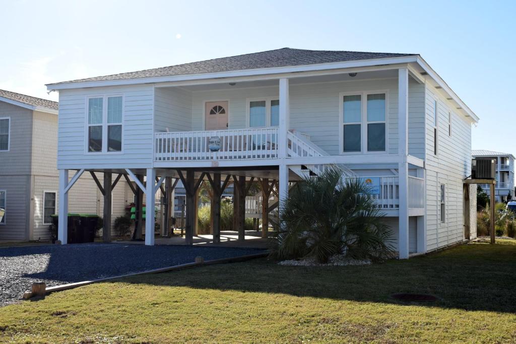 a white house with a porch and a balcony at Keepin It Reel in Holden Beach
