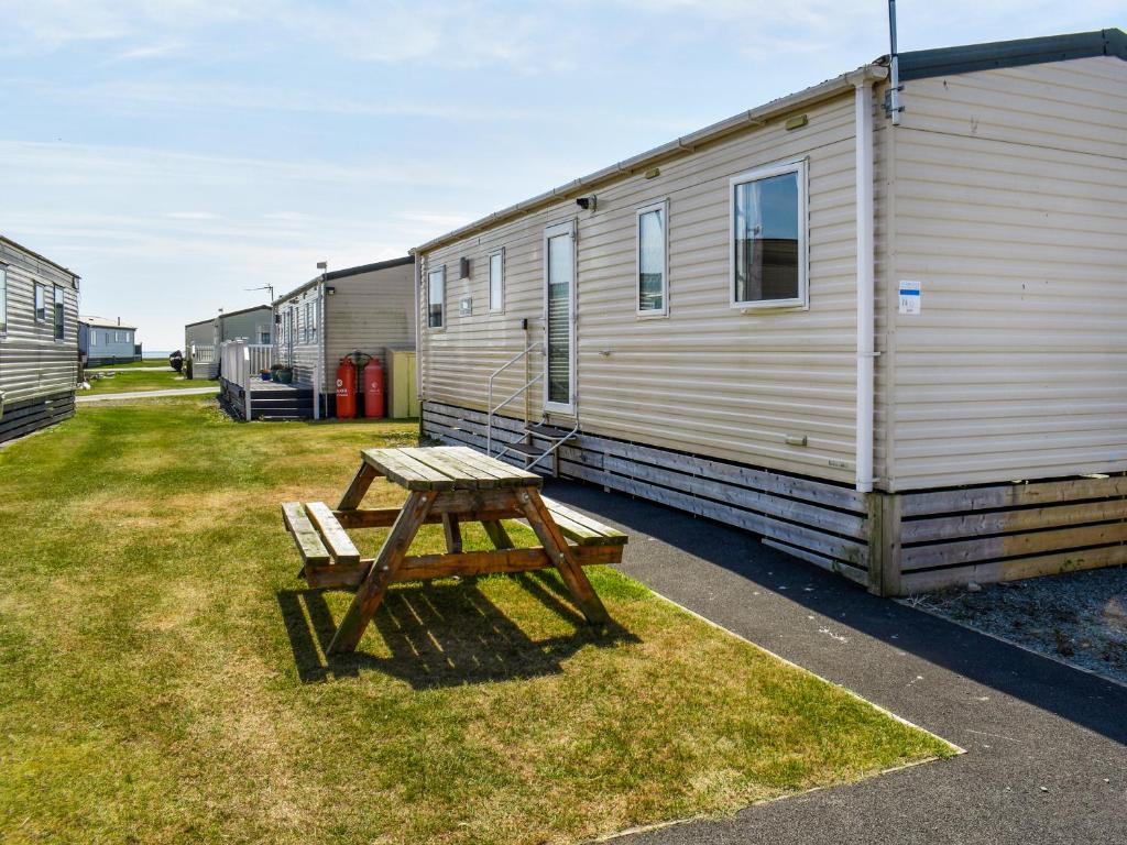 a wooden picnic table in front of a trailer at Waterlily in Lancaster