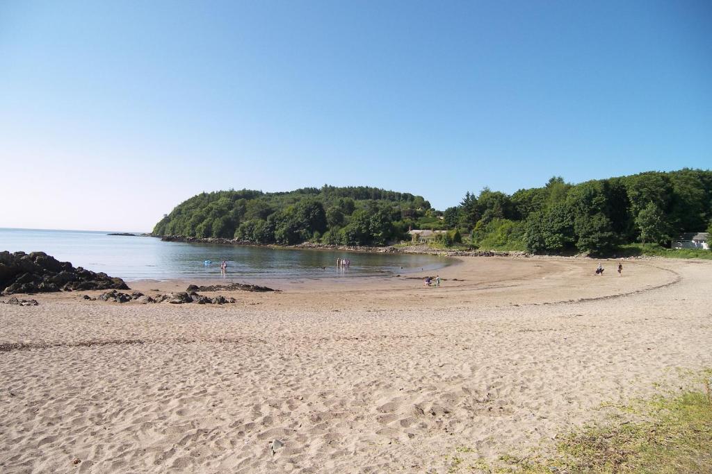 a sandy beach with people swimming in the water at Wee Newton in Twynholm