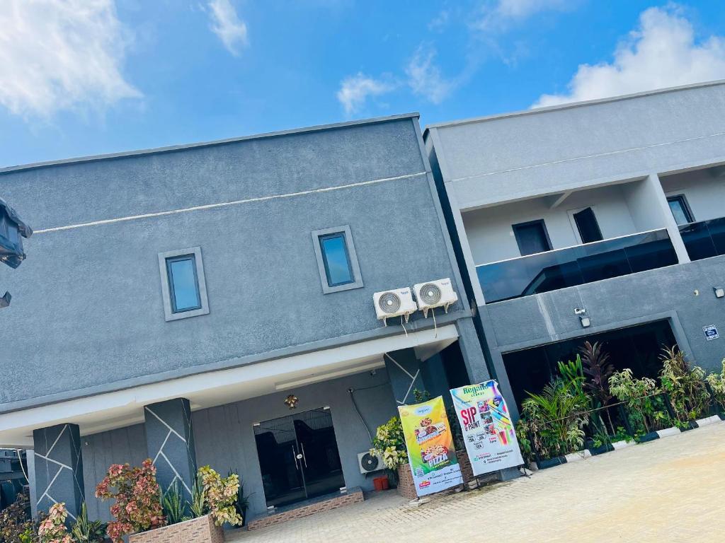 een grijs gebouw met een bord ervoor bij The Majj Hotel Sapele in Sapele