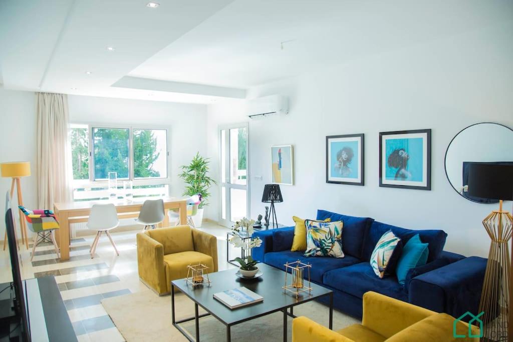 a living room with a blue couch and yellow chairs at Le Premium Central luxueux et très confortable in Dār Şāliḩ Bey