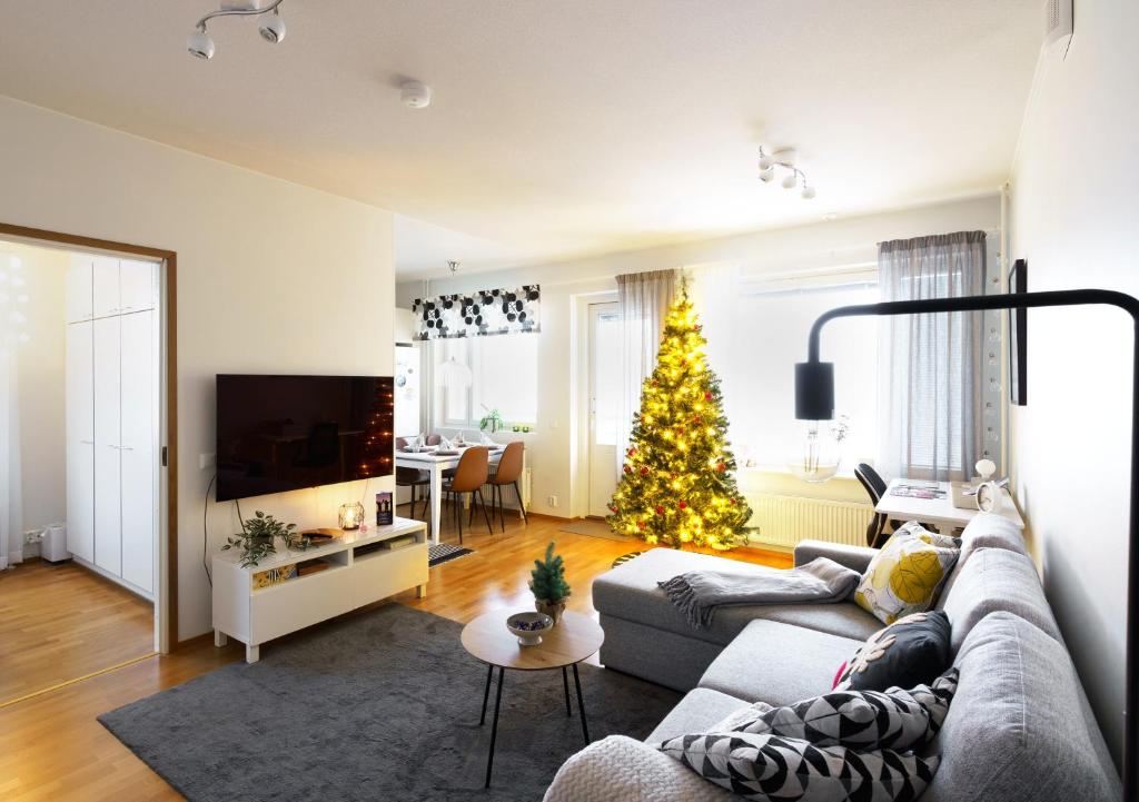 a living room with a christmas tree and a couch at Adorable Arctic Apartments - Private Sauna & Free Parking in Rovaniemi