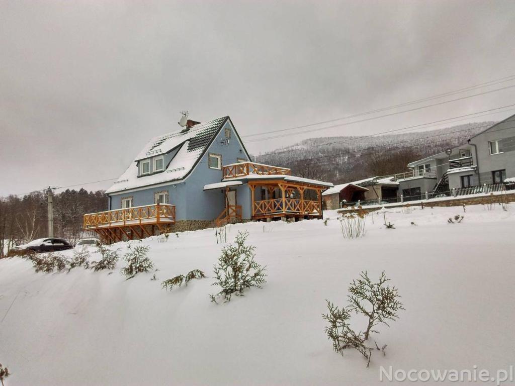 a house in a snow covered yard with houses at Sowi Dom - Jugów in Jugów