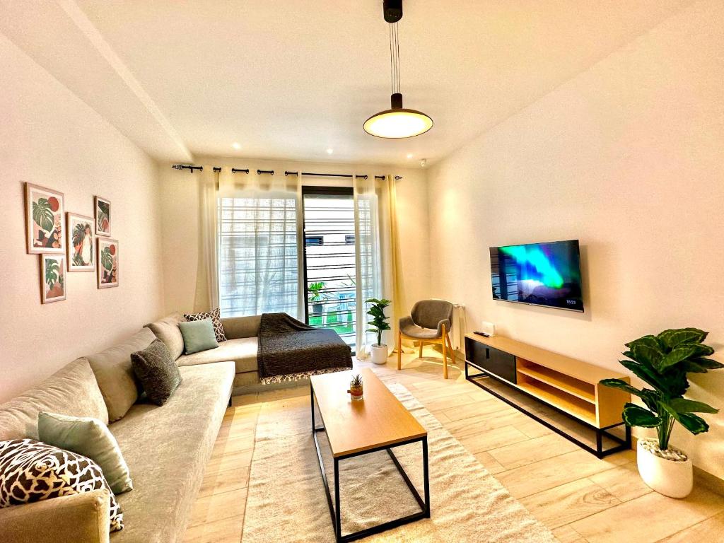a living room with a couch and a tv at Villa Jade appartement neuf avec jardin in Dar el Haj Ahmed Souid