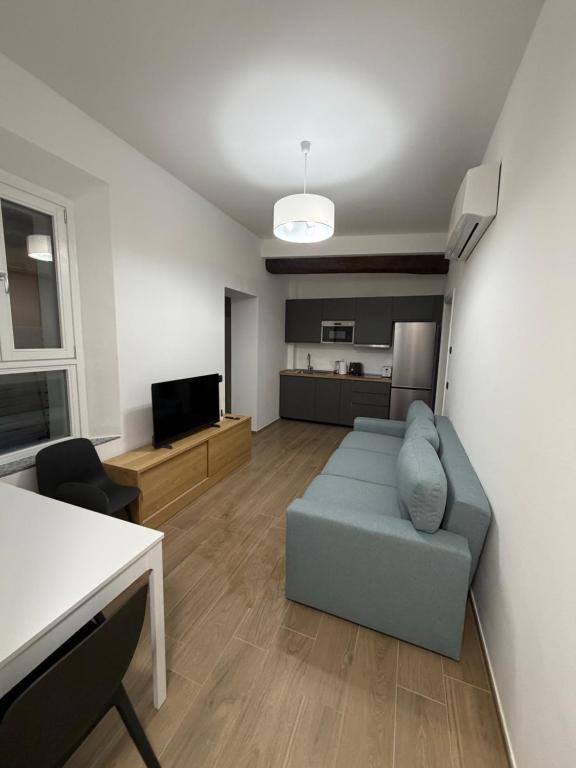 Una sala de estar con un sofá azul y una cocina. en Adriano Space, en Módena