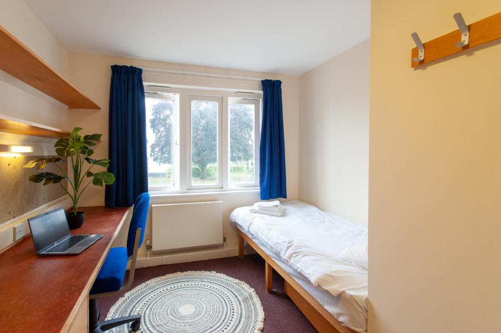 een kamer met een bed, een bureau en een raam bij Villas at Park Campus in Cheltenham