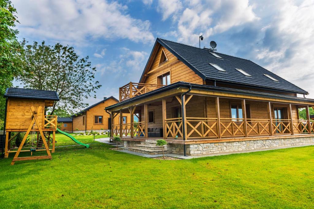 una gran casa de madera con un parque infantil en el patio en Gruszowa Villa, en Kalwaria Pacławska