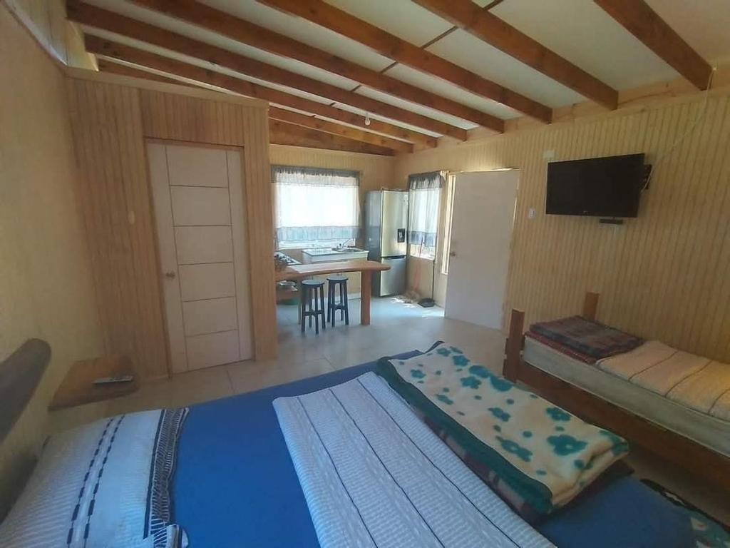 a bedroom with a bed and a living room at Cabañas Entre Bosques De Algarrobo in Algarrobo