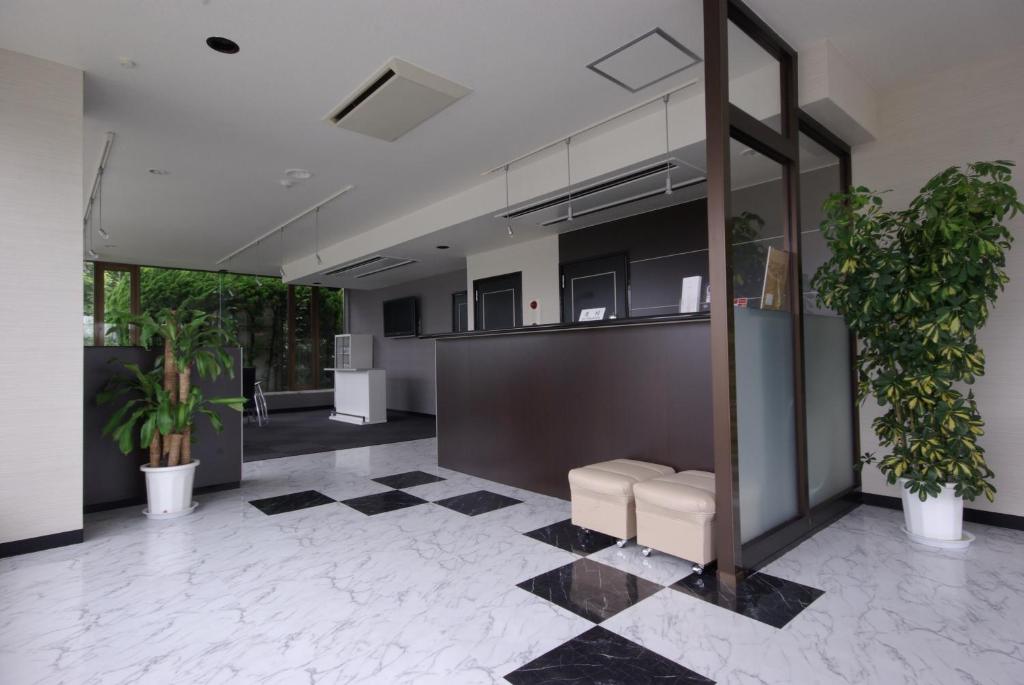 Sakura Hotel Oami في Ōami: لوبي مكتب بالنباتات ومكتب استقبال