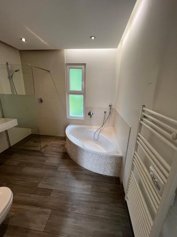 a bathroom with a tub and a toilet and a sink at Work & Travel Lodge Münsingen in Münsingen