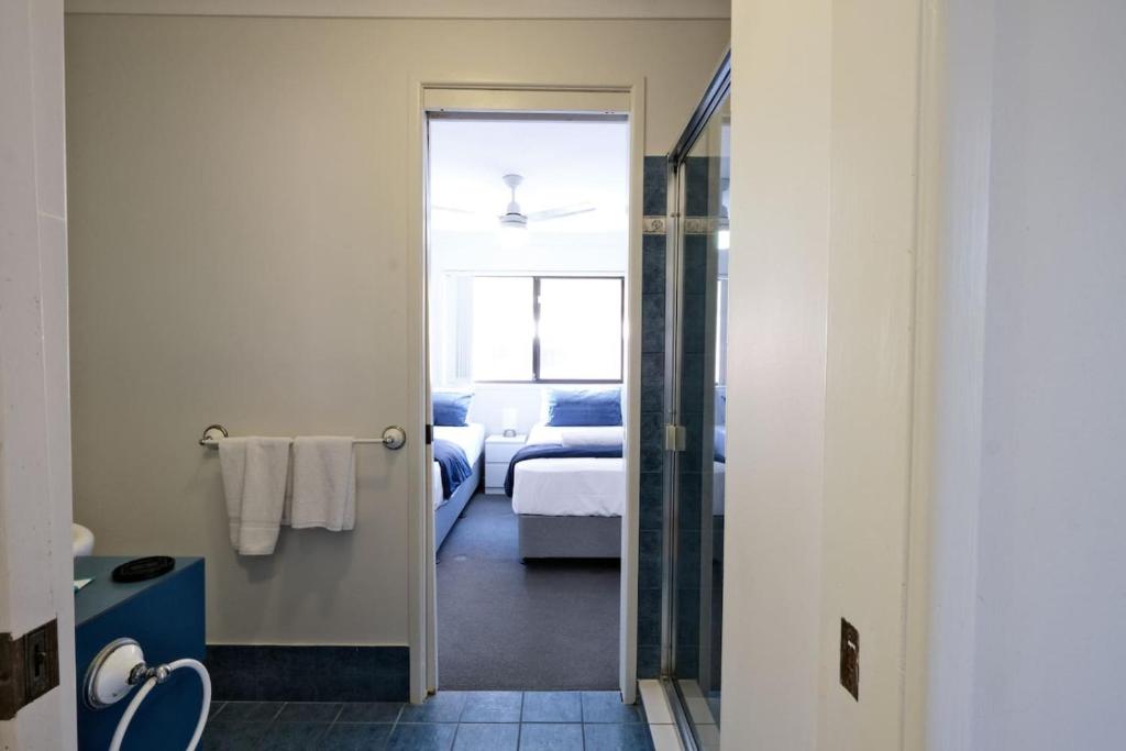 Coastal 2BR Retreat Heart of Broadbeach Living في غولد كوست: غرفة مع غرفة نوم بها سرير وحمام