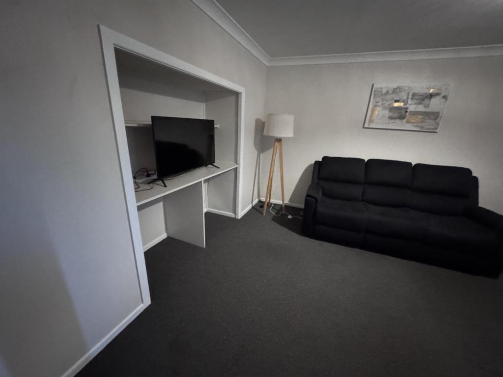 グラフトンにあるApartments on Turf Unit 4のリビングルーム(黒いソファ、テレビ付)