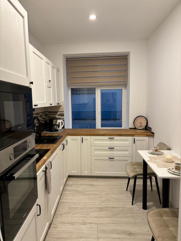 a kitchen with white cabinets and a table and a window at Vecpilsētas apartaments in Cēsis