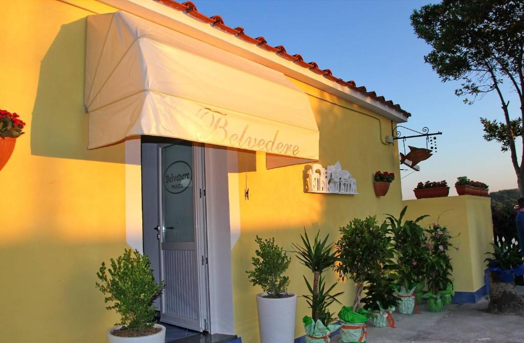 a yellow building with an awning and potted plants at Belvedere in Procida