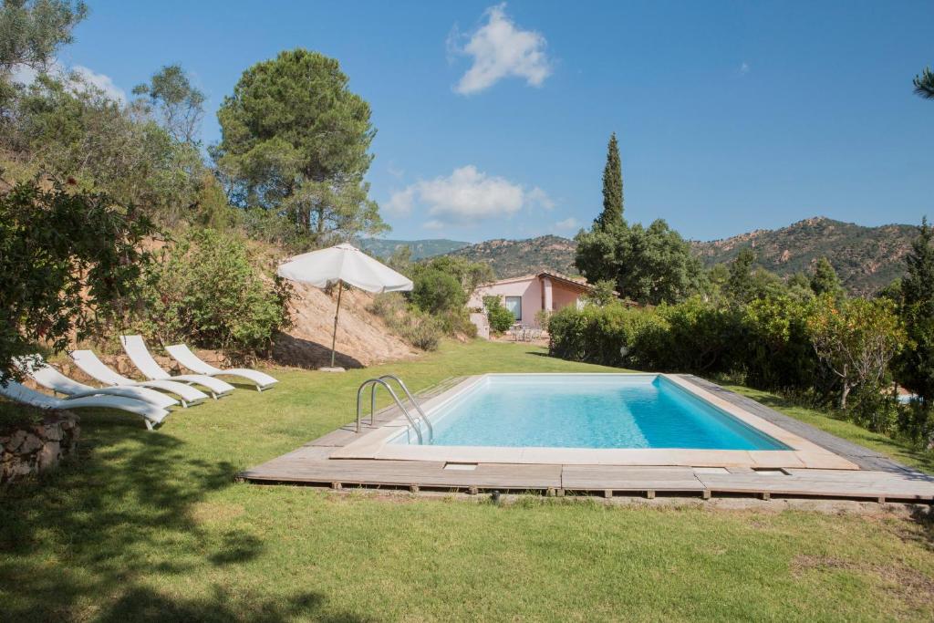 una piscina en un patio con sillas y sombrilla en Finca Fiori 2, en Is Molas 