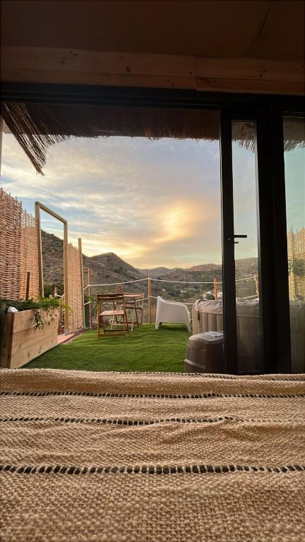 a patio with a table and a view of the mountains at Glamping Cabaña Suite Los Almendros in Málaga