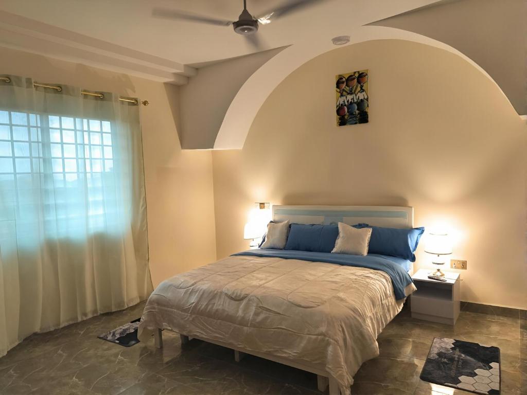 een slaapkamer met een groot bed met een groot raam bij Modern 1 bedroom flats in Tema