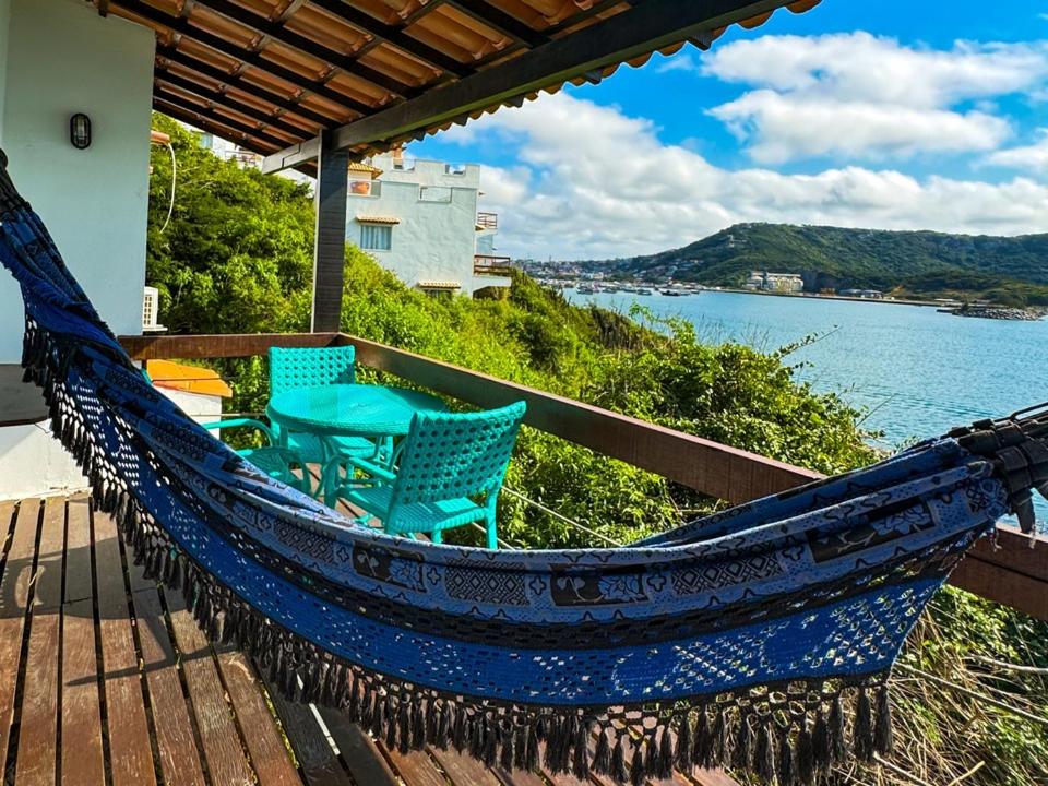 a hammock on a porch with a view of the water at Pousada Vista Grega in Arraial do Cabo
