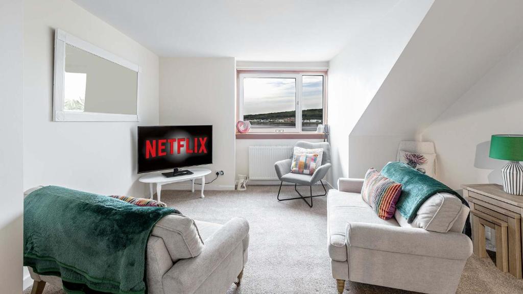 a living room with two chairs and a tv at Sea The View in Rothesay