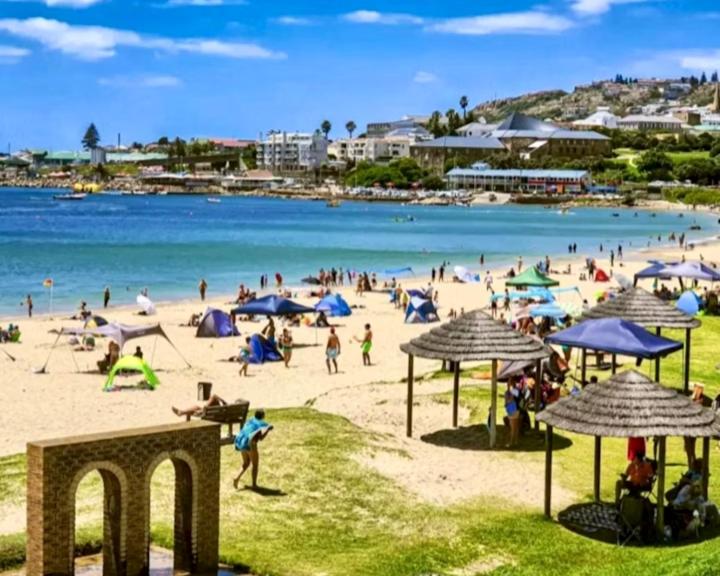 a group of people on a beach with umbrellas at Gemma in Mossel Bay