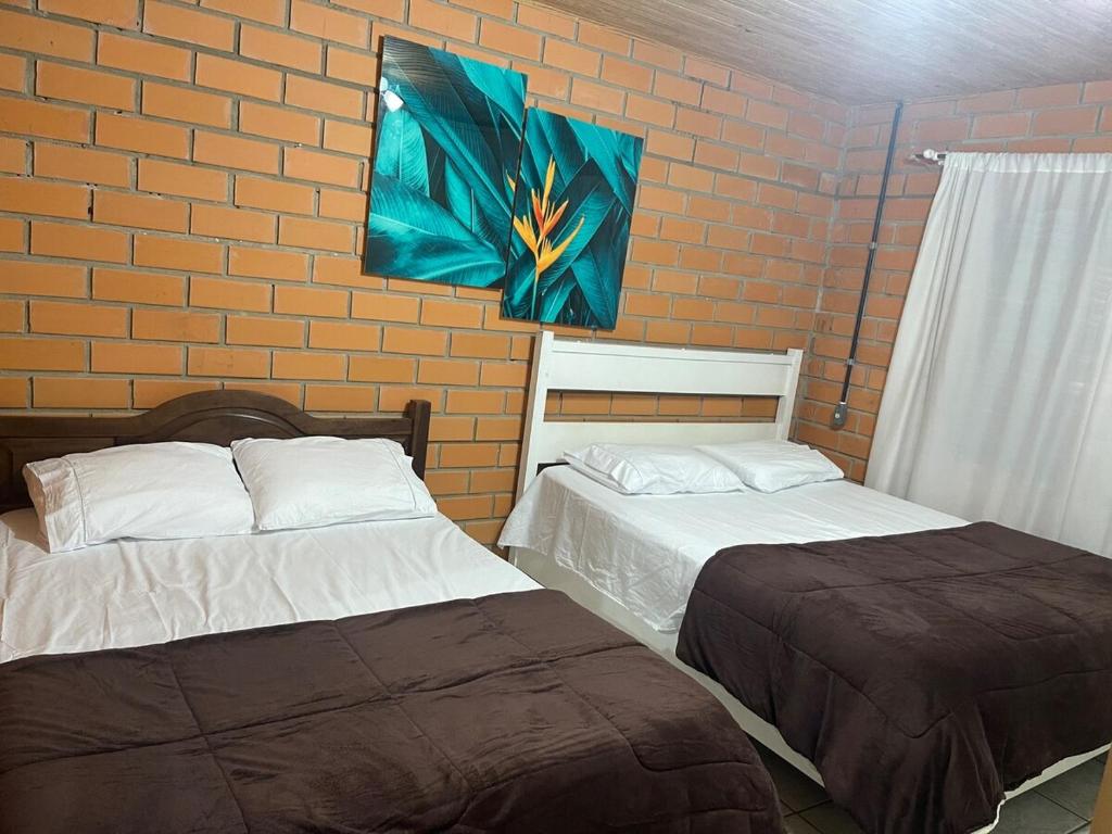 two beds in a room with a brick wall at Sito São Joaquim in Itaquá