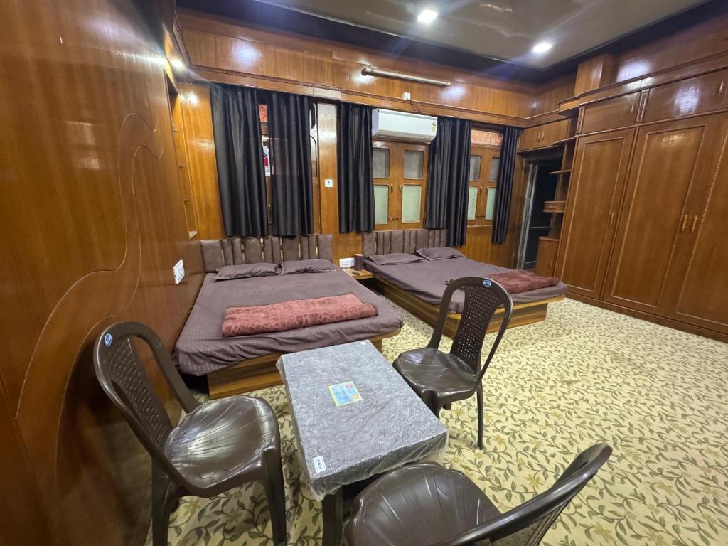 a room with two beds and a table and chairs at Perfect Homestay Ujjain in Ujjain