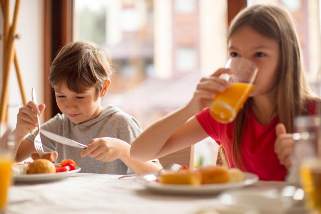 a young girl and boy sitting at a table drinking orange juice at Holiday Inn - the niu, Form Stuttgart Feuerbach by IHG in Stuttgart