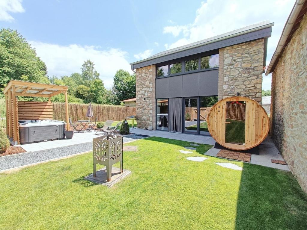 a garden with a barbecue in front of a house at L'école Buissonnière - Suite Bien-être 2 personnes in Vielsalm