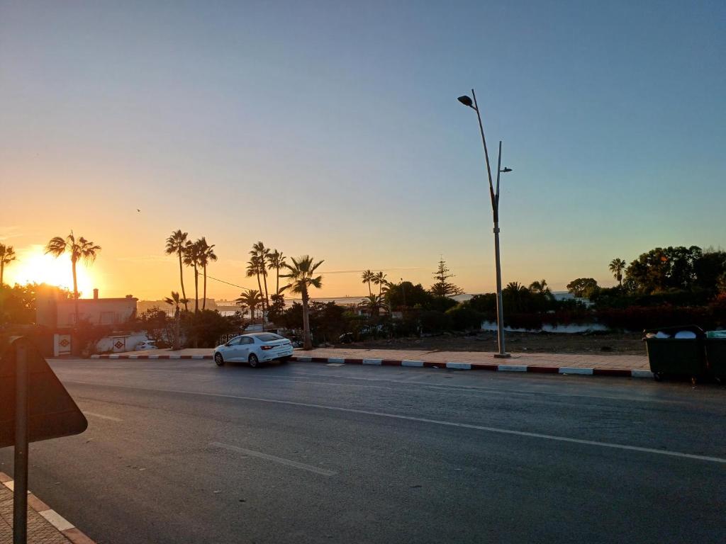 a car parked on the side of a road at sunset at الشروق 2 résidence chourouk 2 in Mansouria