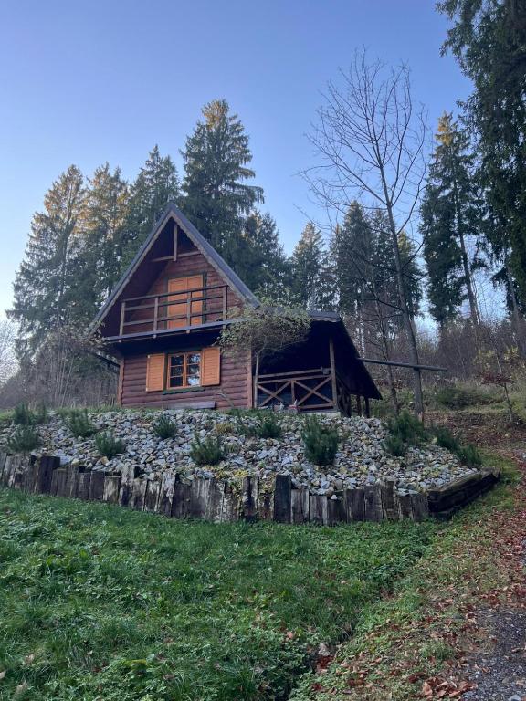 una cabaña de madera en una colina con una pared de piedra en Chata u Zbojníka, en Oravský Podzámok
