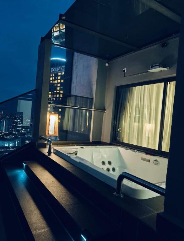 a bathroom with a bath tub with a view of a city at Jacuzzi with Starry Sky Bedroom-7pax in Malacca