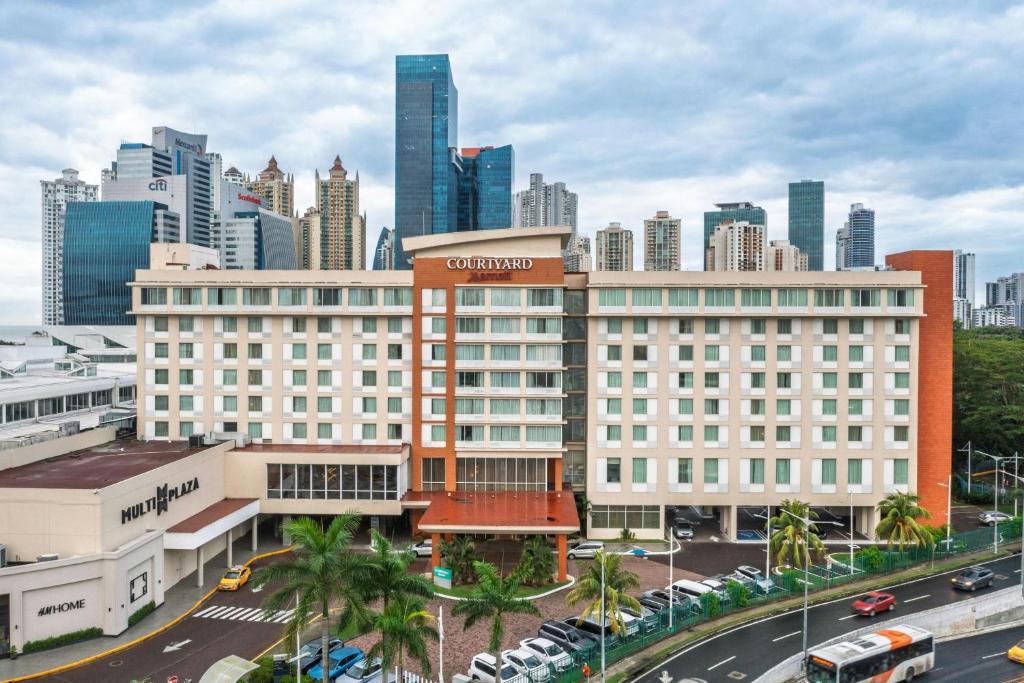 a large white building in front of a city at Courtyard by Marriott Panama Multiplaza Mall in Panama City