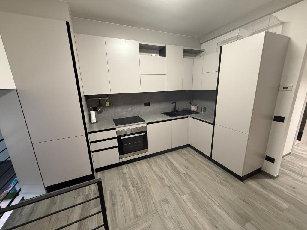 een lege keuken met witte kasten en een koelkast bij Il Paese delle Vacanze by Elisa in Omegna