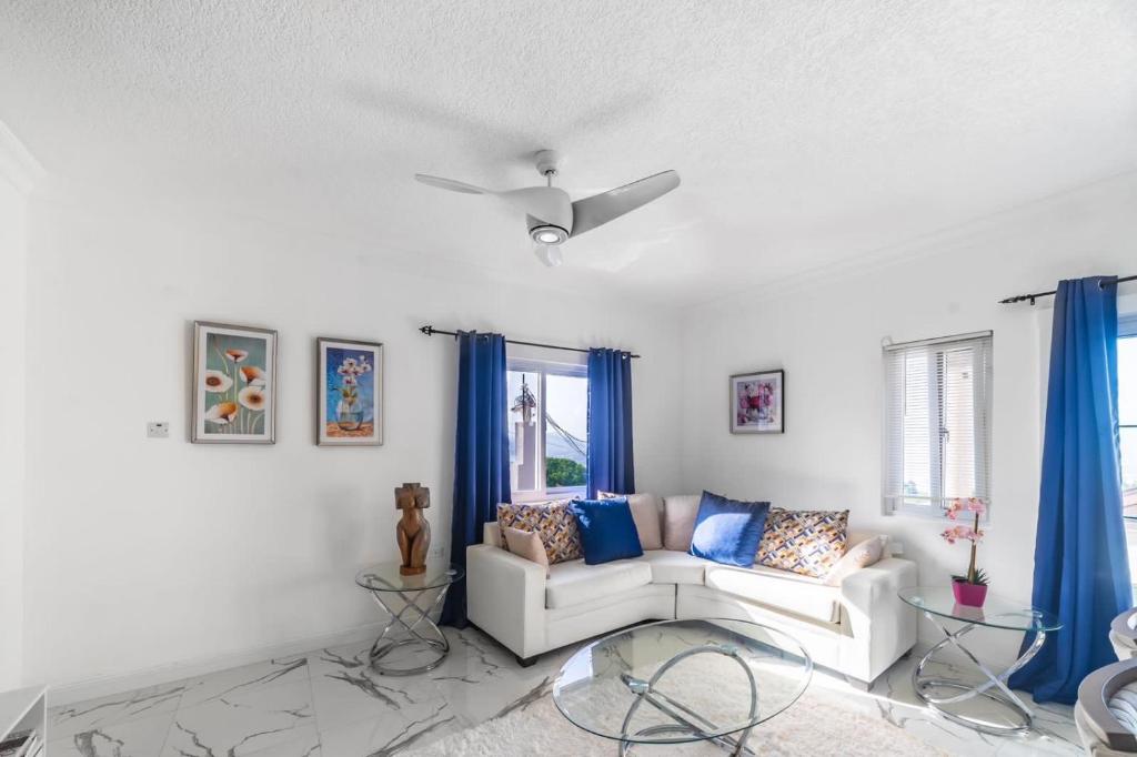 a living room with a white couch and blue curtains at Hibiscus Charm in Red Hills