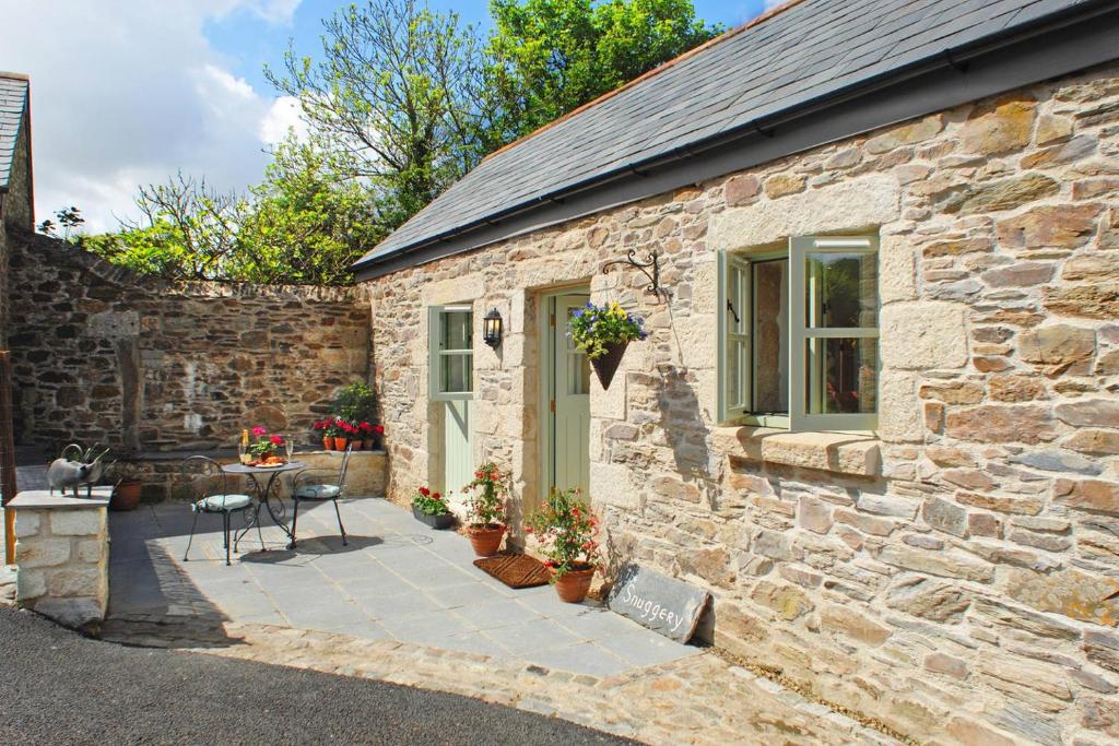 a stone house with a patio and a table at The Snuggery in Truro