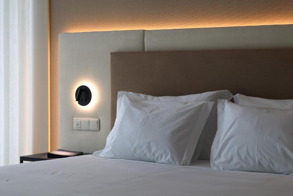 a bedroom with a bed with white pillows at Oporto Fly Hotel in Maia