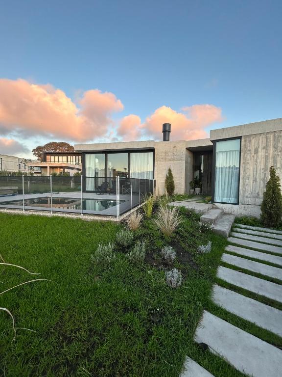 a building with glass doors and a lawn at Casa Rumenco Joven mdq in Mar del Plata