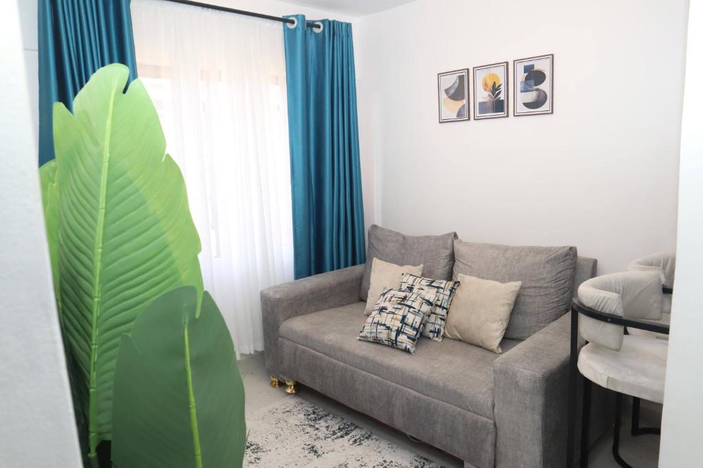 a living room with a couch and a plant at Makasembo Cozy Serenity in Kisumu