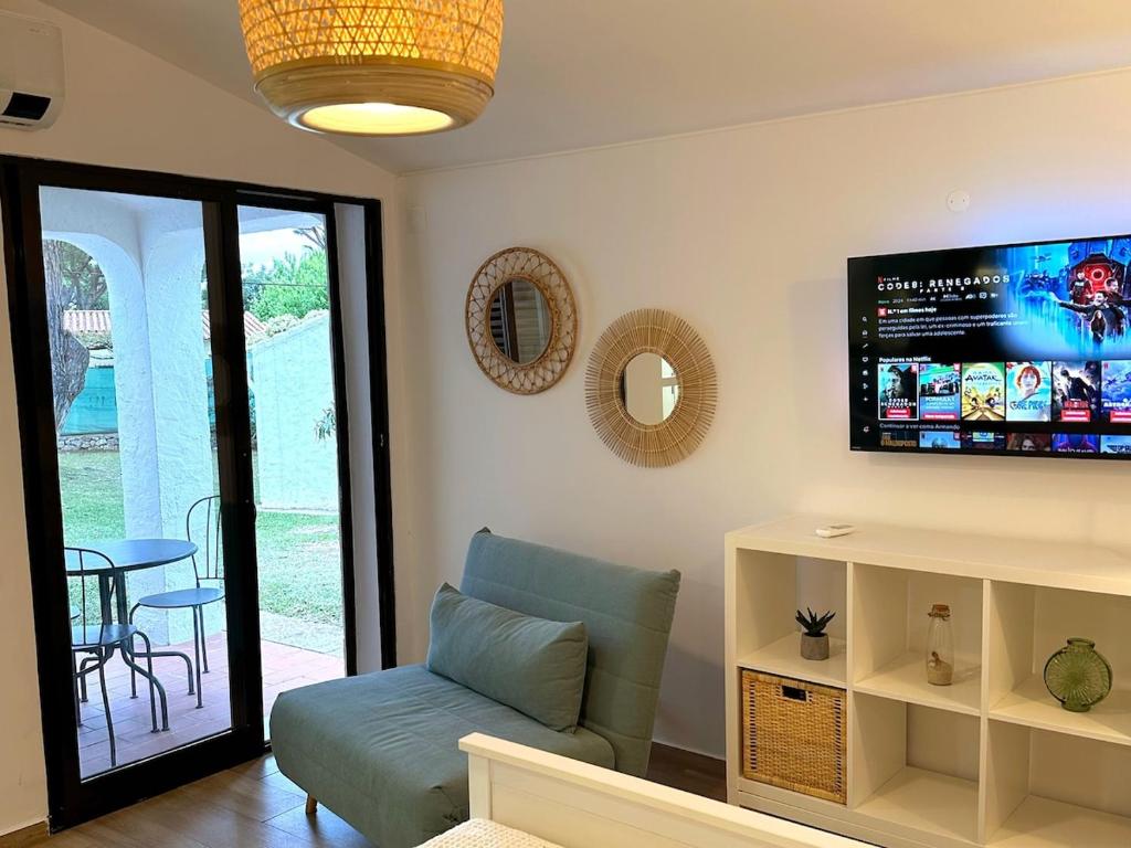 Una sala de estar con un sofá y un televisor de pantalla plana. en Refúgio junto à falésia, en Olhos de Água